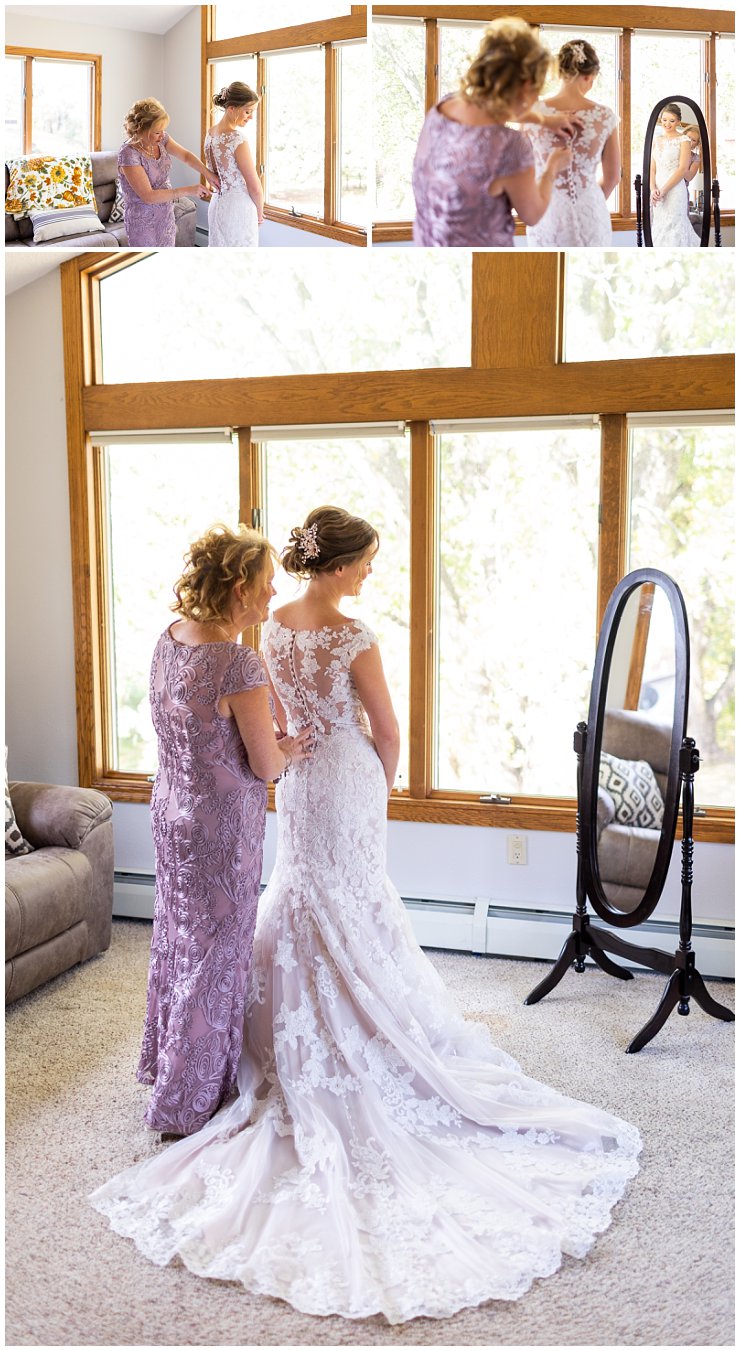 Mother helping bride with dress while looking in the mirror